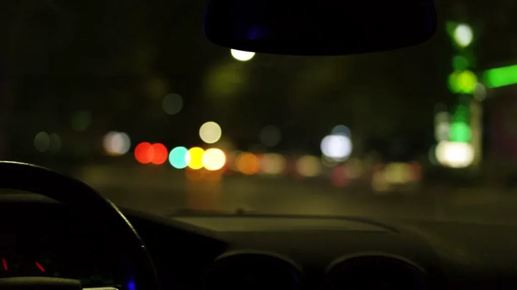 Night view of a city street through a car windshield with blurred lights